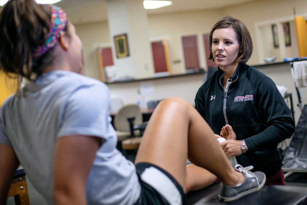 Athletic training talks with student athlete in training lab