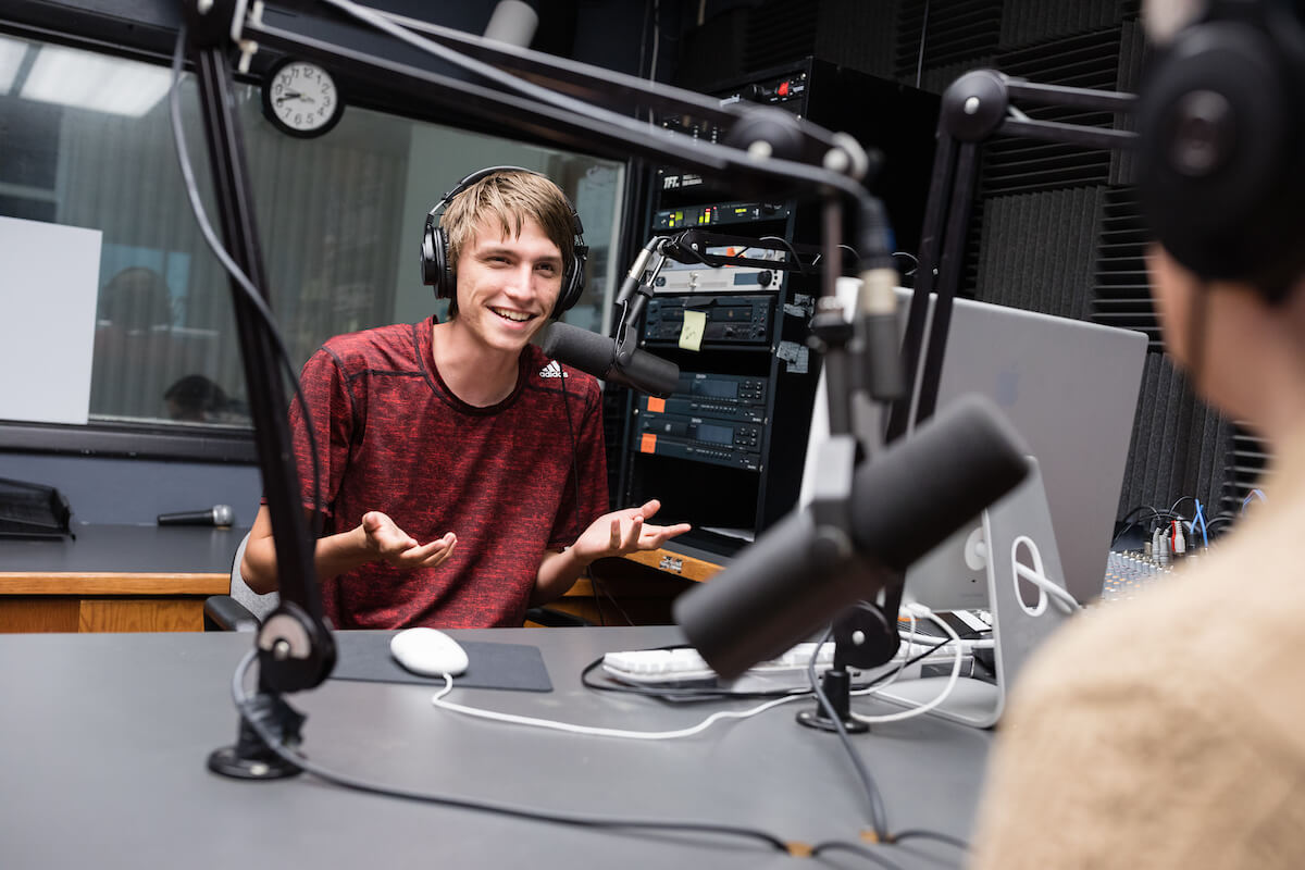 Student wearing headphones talks on mic during podcast