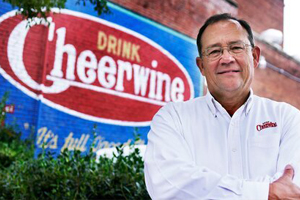 Cliff Ritchie '76 stands in front of Drink Cheerwine mural on building